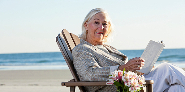 Senior woman reading book on beach
